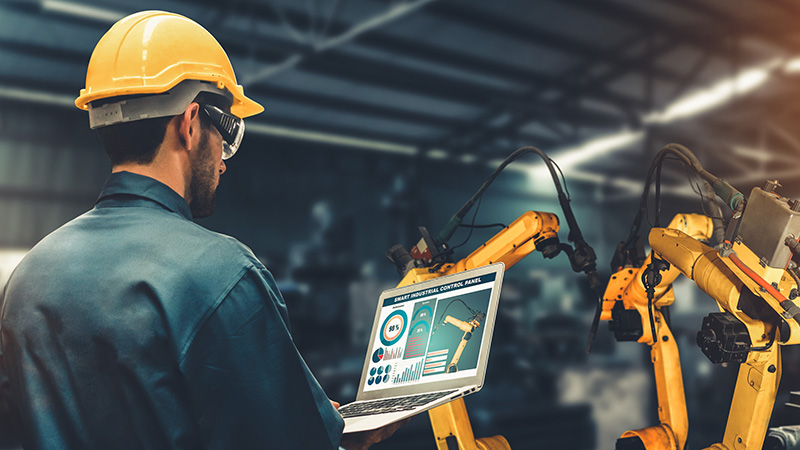 man working in factory with robot arms